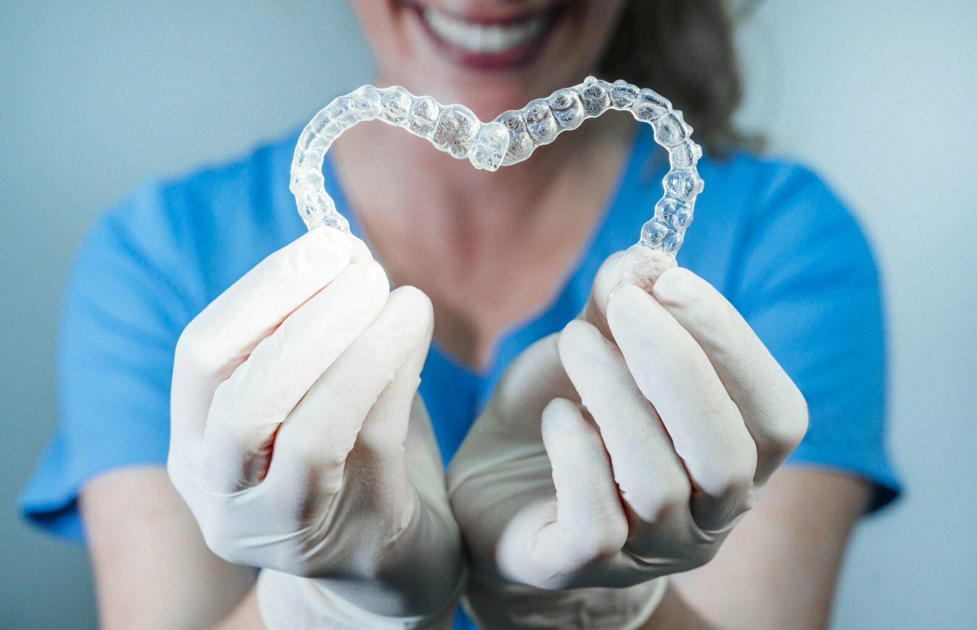 Female doctor holding two transparent heart-shaped dental aligner
