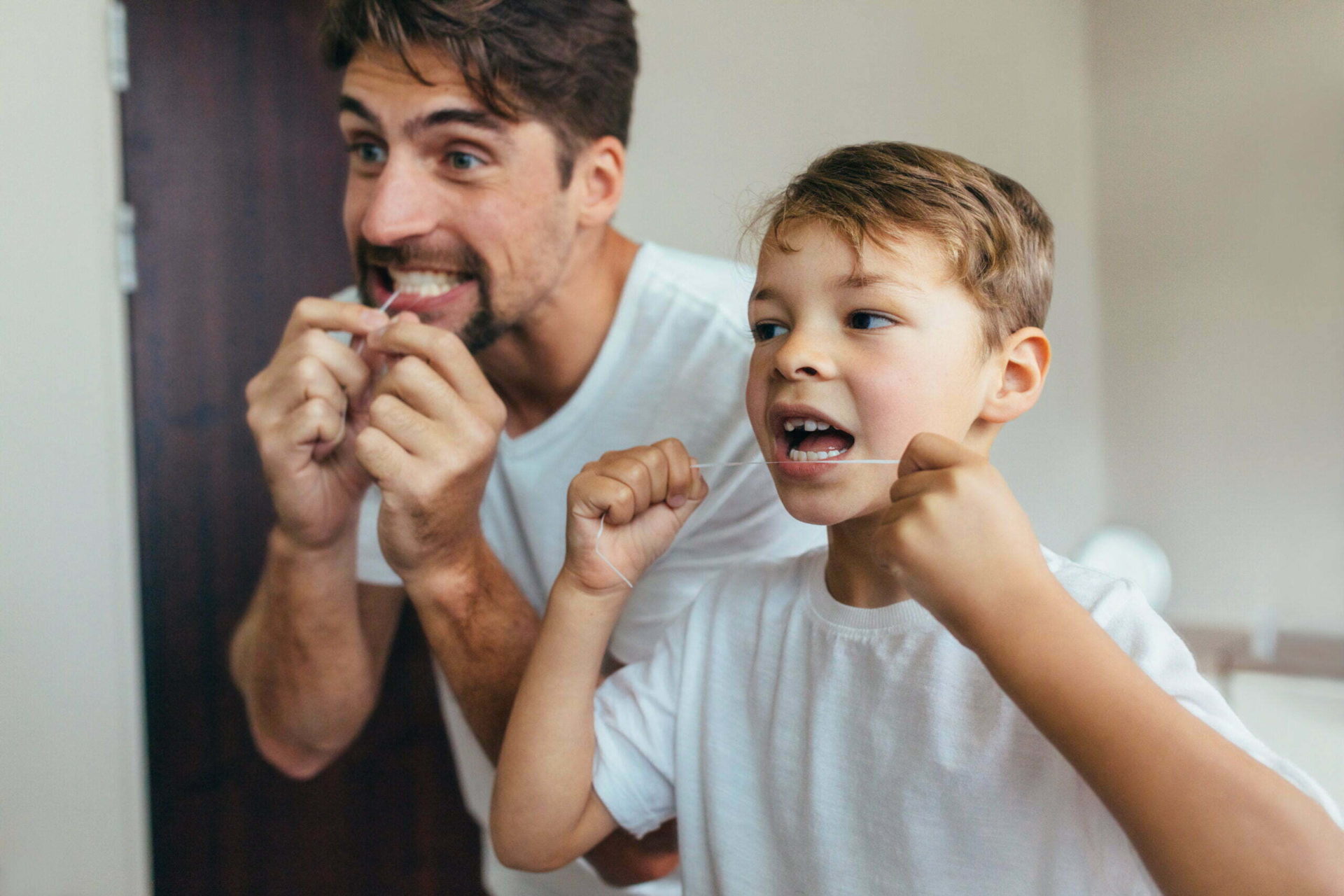 Little boy with his father in bathroom cleaning teeth with dental floss