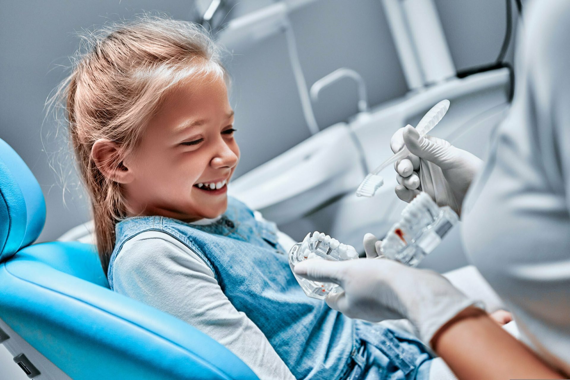 The dentist tells the child about oral hygiene and shows an artificial jaw and toothbrush