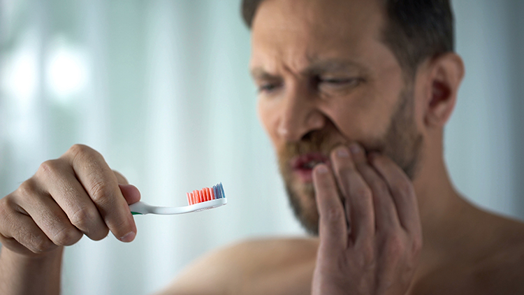 Man holding a toothbrush and his mouth
