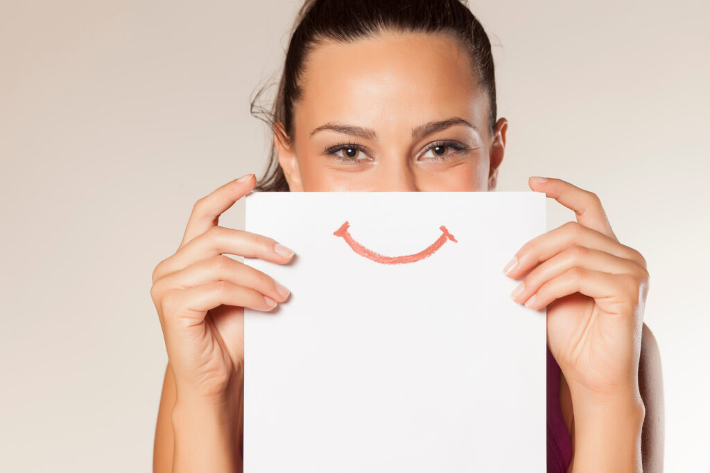 Woman holding a smile on a piece of paper