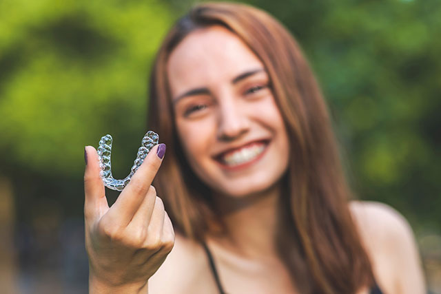 Woman smiling holding a clear aligner