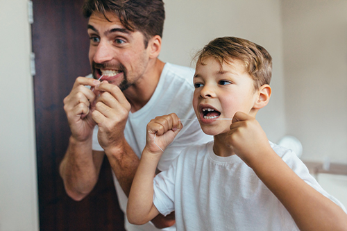 Man and child flossing their teeth 