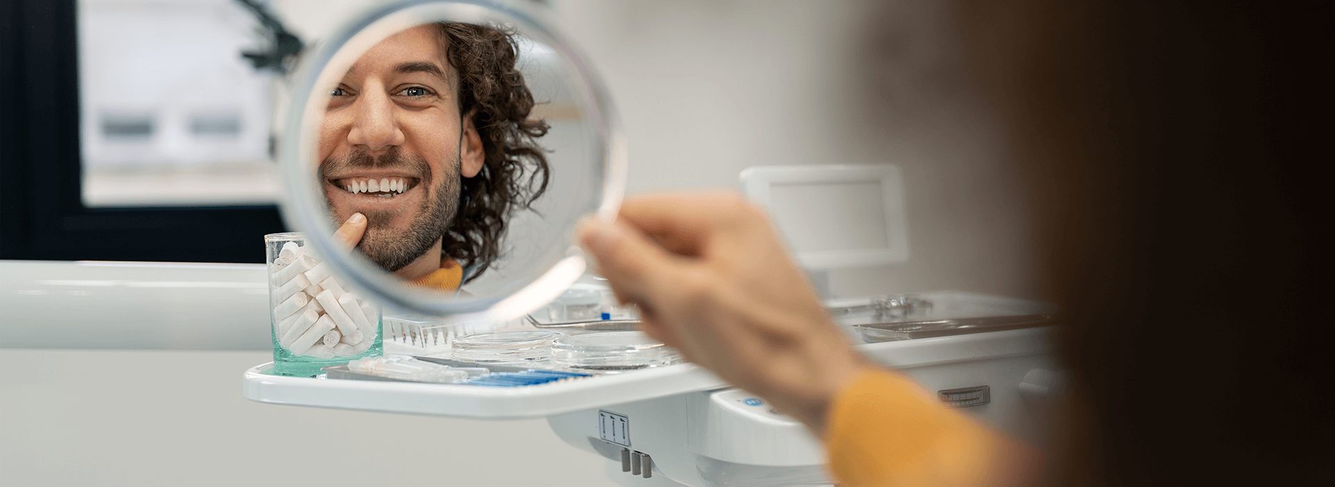 Man in dentist smiling into a mirror