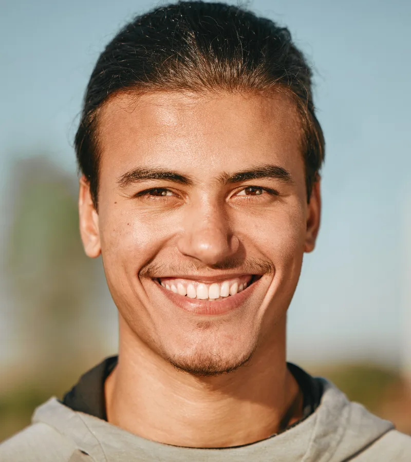 Young man smiling confidently after gum disease treatment at Aesthetique Dental Care in Leeds, showing healthy gums and improved oral health.