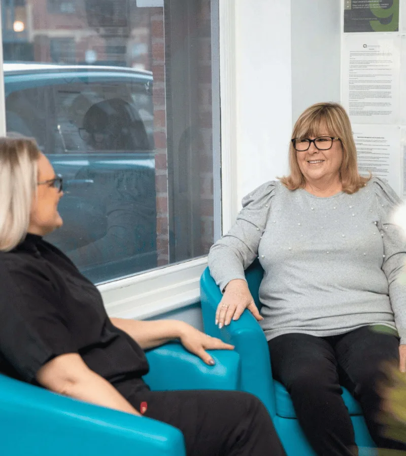 Debbie, Practice Manager at Aesthetique Dental Care in Leeds, speaking with a patient in the reception area, offering support and guidance before their appointment.